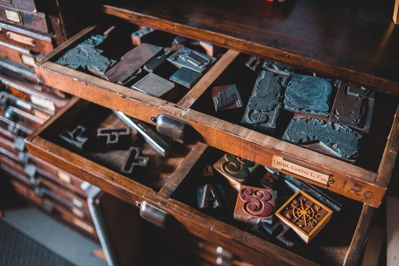 Drawers of metal letterpress type in a wooden cabinet, in ink duotone.